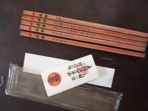 Japanese prayer/shrine/good-luck pencils. Pencils have a natural wood barrel with black printed text below a splashy red circle as describe in the post.